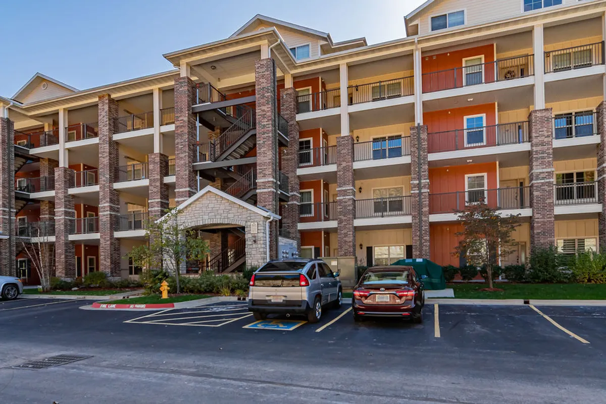 This shot highlights the brick facade of the building, featuring a staircase, entrance canopy, and a welcoming front area with a visible parking zone. It conveys the ease of access and the communal feel of the property’s entrance, hinting at both arrival and social interactions among guests.