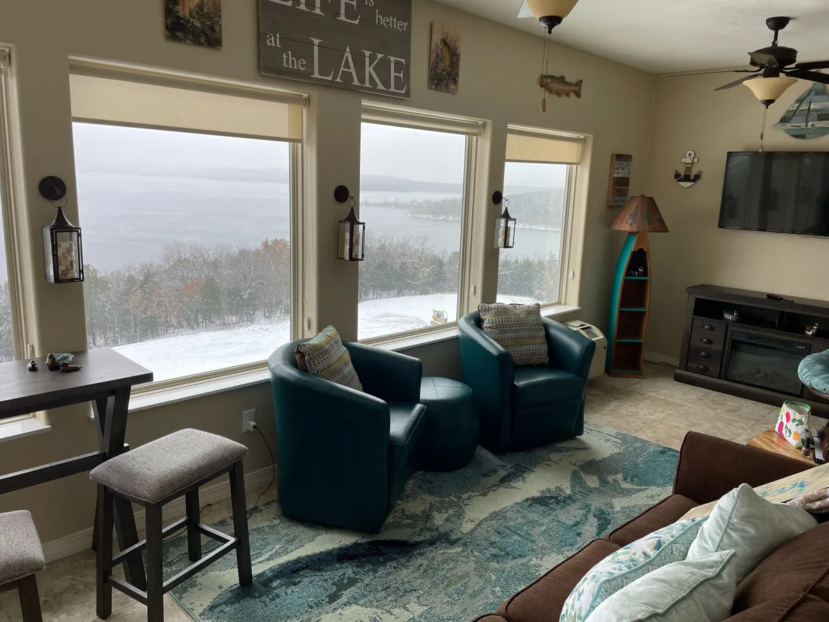 A bright, tranquil space with large windows overlooking the lake, comfortable seating, and tasteful wall art, ideal for reading, enjoying coffee, or gathering together.