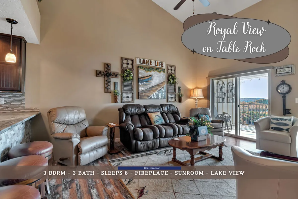 This image features a comfortable seating arrangement in a sunroom with large windows offering a panoramic view of Table Rock Lake. Decorative wall art adds character, and the presence of an electric fireplace enhances the cozy, adaptable atmosphere ideal for both intimate relaxation and group gatherings.