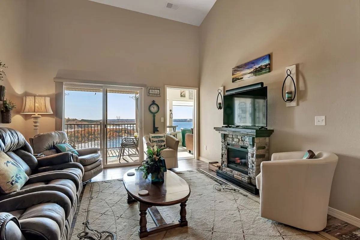 A spacious, comfortable seating area with a fireplace, large windows that provide plenty of natural light, and decorative artwork on the walls. The arrangement invites group gatherings and quiet relaxation, offering multiple seating options to suit different activities.