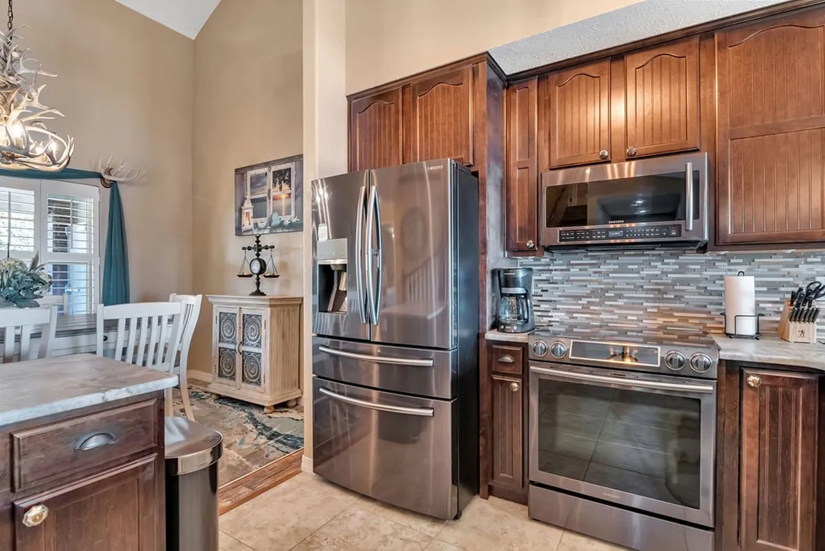 A modern kitchen with gleaming stainless steel appliances, a marble countertop, warm wood cabinetry, and tasteful wall art. The space is ideal for cooking holiday meals, casual breakfasts, or preparing snacks for an outdoor adventure.