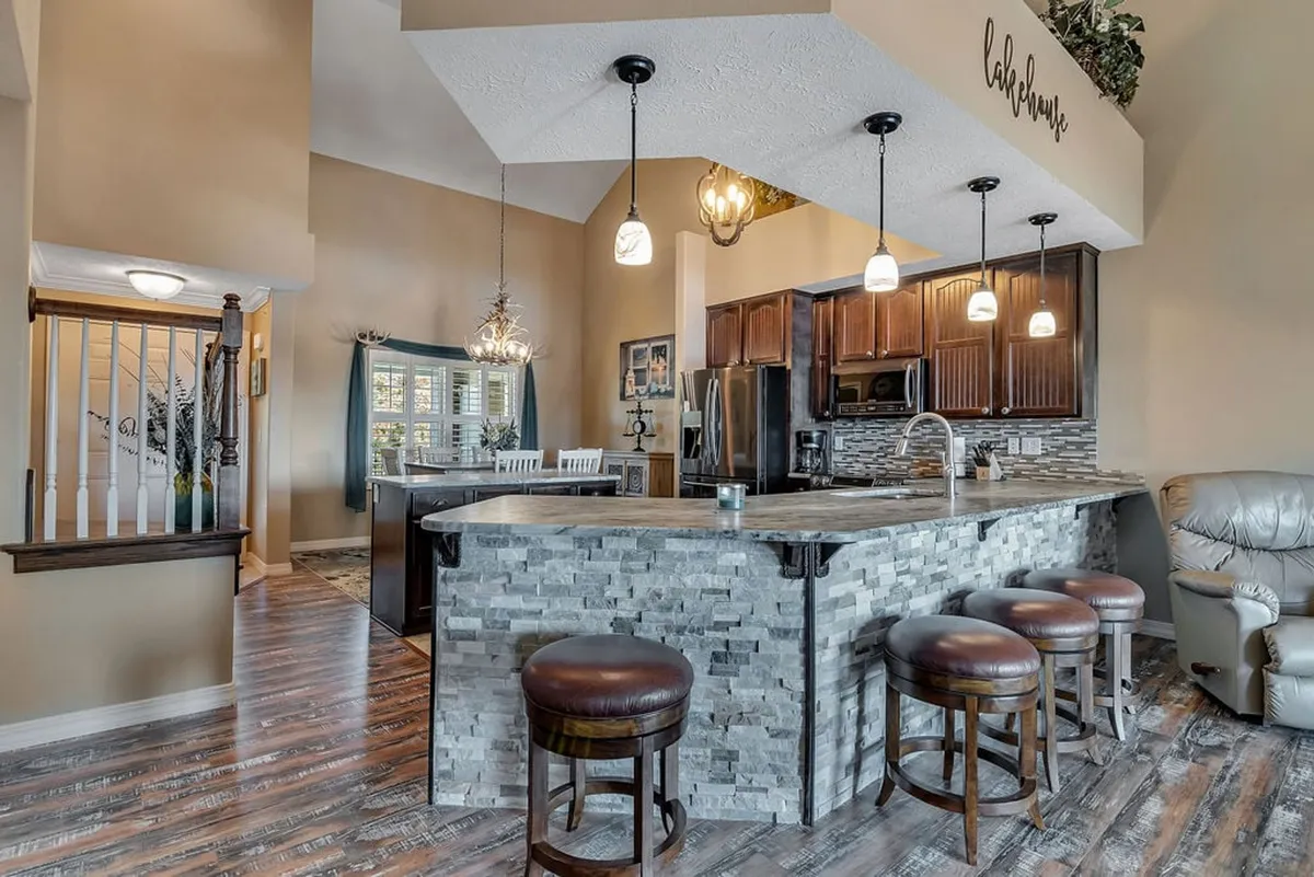 This angle shows a stylish kitchen island with bar stools and an adjacent dining area. Decorative lighting and warm accents create an atmosphere that's both inviting and ideal for entertaining or enjoying casual meals. The layout emphasizes togetherness and social interaction.